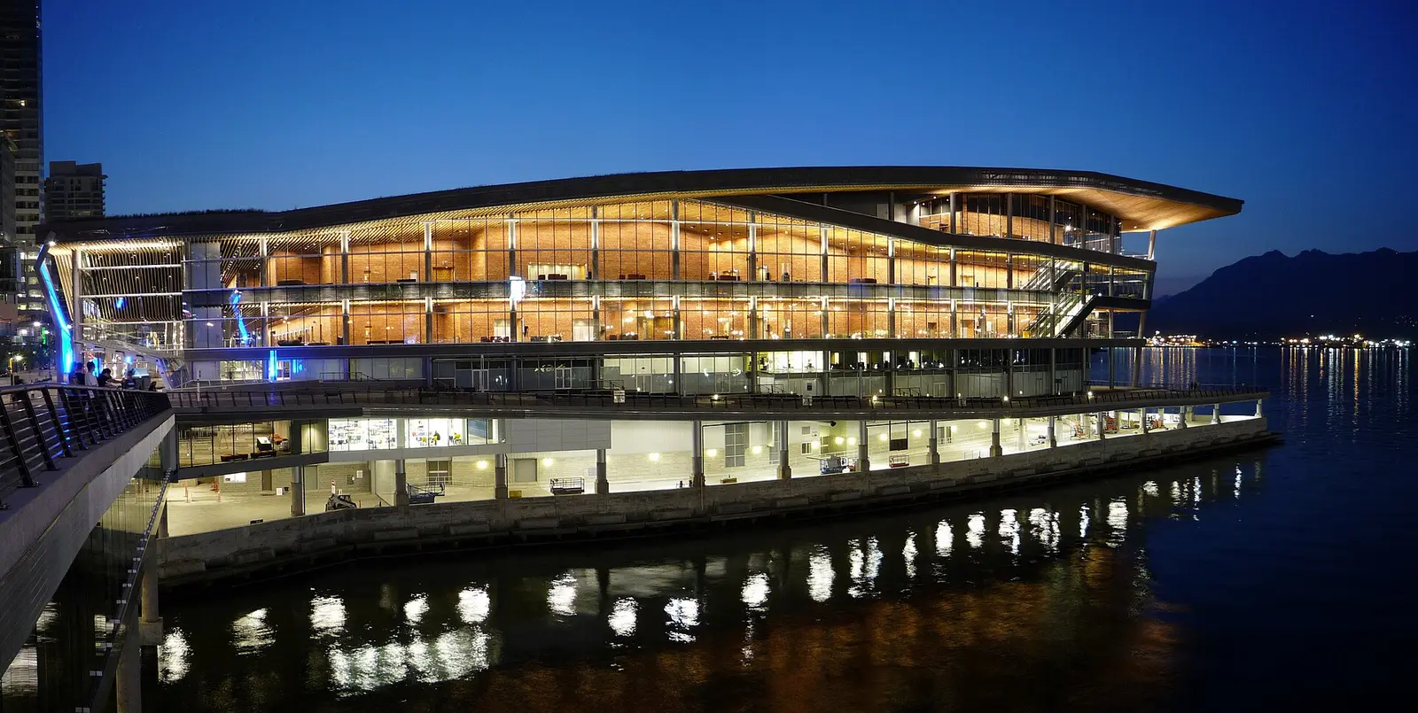 The Vancouver Convention Centre West Building lit up at dusk beside the harbour